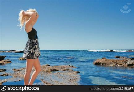 beautiful young woman on the reef rocks at the sea