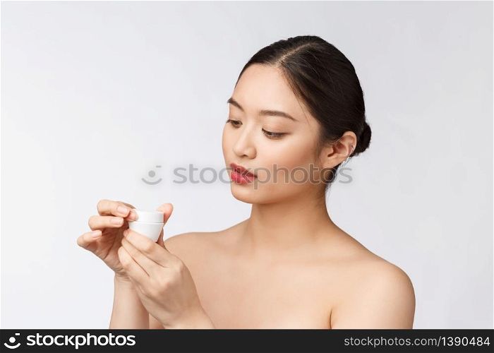 Beautiful young woman on white isolated background holding cosmetic face cream, asian.. Beautiful young woman on white isolated background holding cosmetic face cream, asian