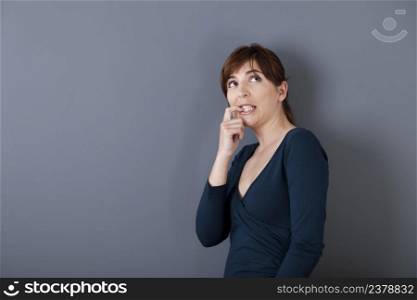 Beautiful young woman over a gray background thinking in something