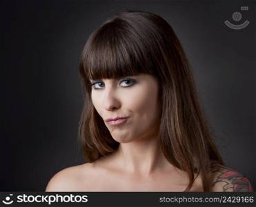 Beautiful young woman over a grey backround with a funny expression