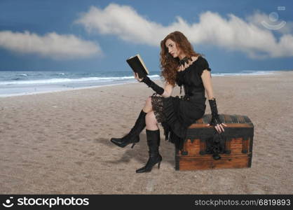 Beautiful young woman pirate reading a book treasure chest