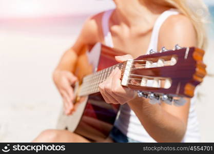 Beautiful young woman playing guitar on beach. Beautiful young smiling woman playing guitar on beach