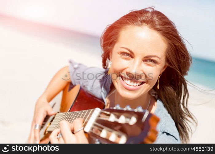 Beautiful young woman playing guitar on beach. Beautiful young smiling woman playing guitar on beach