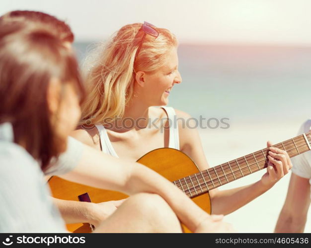 Beautiful young woman playing guitar on beach. Beautiful young smiling woman playing guitar on beach