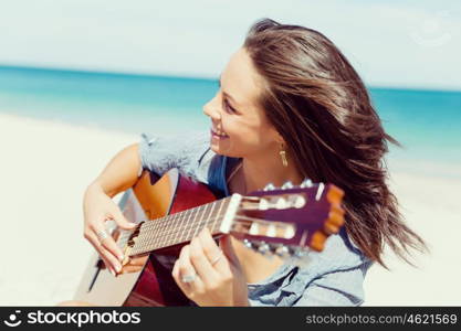 Beautiful young woman playing guitar on beach. Beautiful young smiling woman playing guitar on beach
