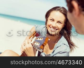 Beautiful young woman playing guitar on beach. Beautiful young smiling woman playing guitar on beach