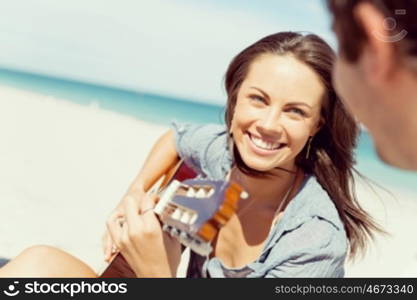 Beautiful young woman playing guitar on beach. Beautiful young smiling woman playing guitar on beach