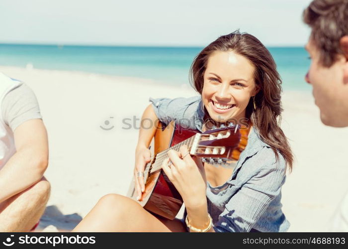 Beautiful young woman playing guitar on beach. Beautiful young smiling woman playing guitar on beach