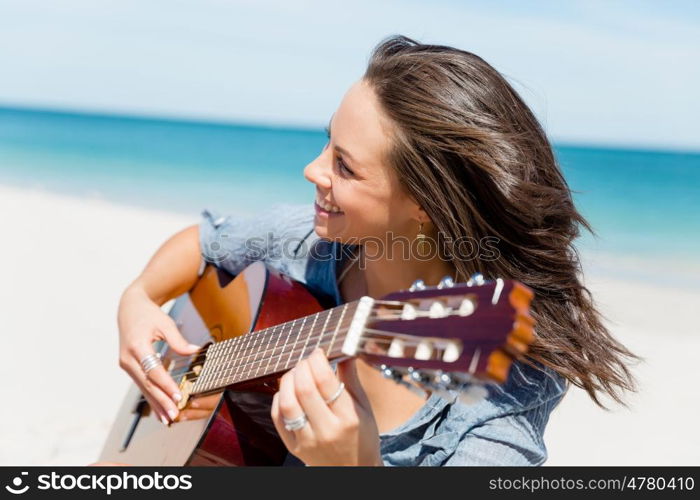 Beautiful young woman playing guitar on beach. Beautiful young smiling woman playing guitar on beach