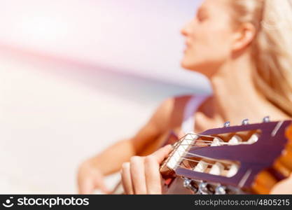 Beautiful young woman playing guitar on beach. Beautiful young smiling woman playing guitar on beach