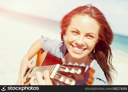 Beautiful young woman playing guitar on beach. Beautiful young smiling woman playing guitar on beach