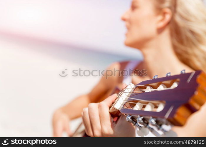 Beautiful young woman playing guitar on beach. Beautiful young smiling woman playing guitar on beach