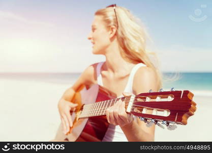 Beautiful young woman playing guitar on beach. Beautiful young smiling woman playing guitar on beach