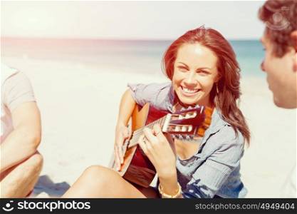 Beautiful young woman playing guitar on beach. Beautiful young smiling woman playing guitar on beach