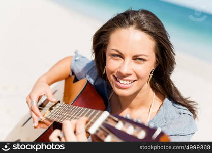 Beautiful young woman playing guitar on beach. Beautiful young smiling woman playing guitar on beach