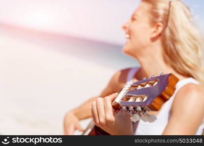 Beautiful young woman playing guitar on beach. Beautiful young smiling woman playing guitar on beach