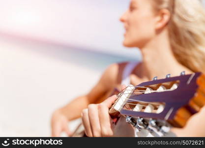 Beautiful young woman playing guitar on beach. Beautiful young smiling woman playing guitar on beach