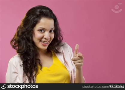 Beautiful young woman pointing against colored background