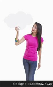 Beautiful young woman pointing at thought bubble over white background