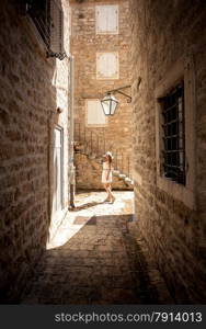 Beautiful young woman posing on old narrow street at sunny day