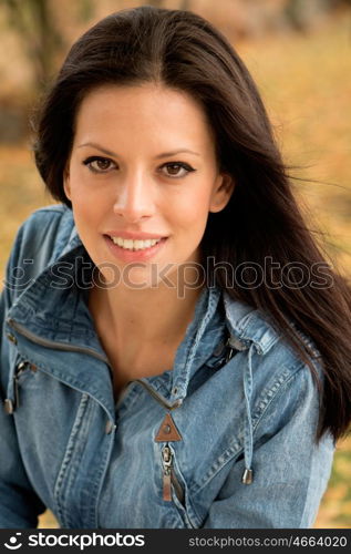 Beautiful young woman reading a book sitting on a bench in park at fall