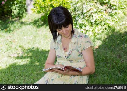 beautiful young woman reading book at park