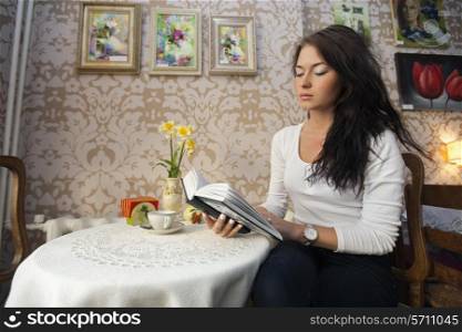 Beautiful young woman reading book in cafe