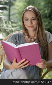 Beautiful young woman reading book in park