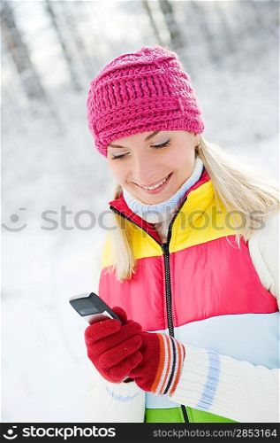 Beautiful young woman reading sms on her cellular phone