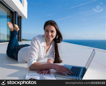 beautiful young woman relax and work on laptop computer and read book at modern home