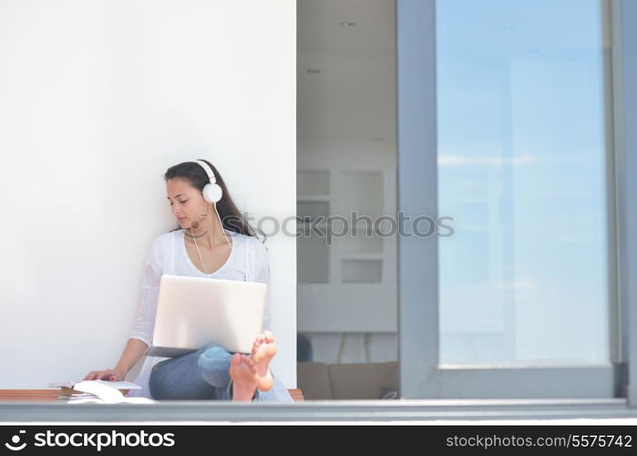 beautiful young woman relax and work on laptop computer while listening music on heaphones and read book at home