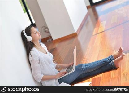 beautiful young woman relax and work on laptop computer while listening music on heaphones and read book at home