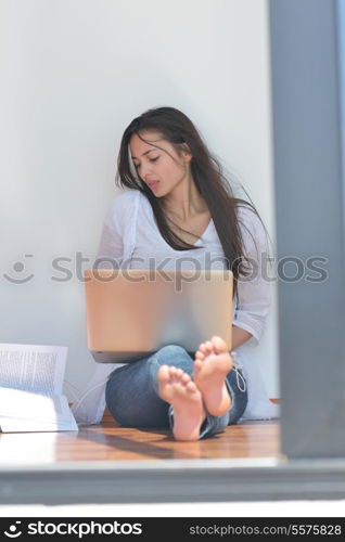 beautiful young woman relax and work on laptop computer while listening music on heaphones and read book at home