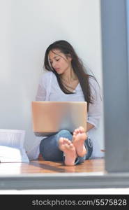 beautiful young woman relax and work on laptop computer while listening music on heaphones and read book at home