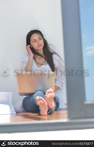 beautiful young woman relax and work on laptop computer while listening music on heaphones and read book at home