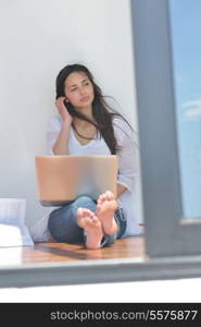 beautiful young woman relax and work on laptop computer while listening music on heaphones and read book at home