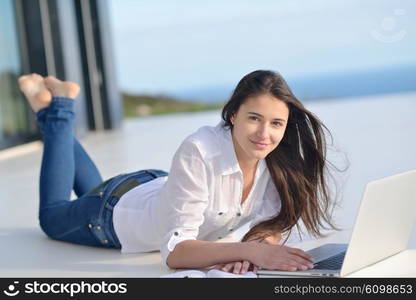 beautiful young woman relax and work on laptop computer while listening music on heaphones and read book at home