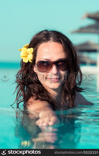 Beautiful young woman relax in swimming pool on tropical resort. Summer vacations concept
