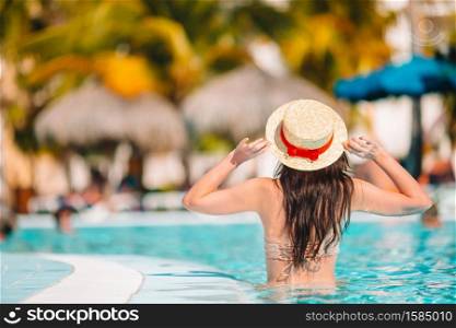 Beautiful young woman relaxing in swimming pool. Girl in bikini in outdoor pool at luxury hotel. Beautiful young woman relaxing in swimming pool.