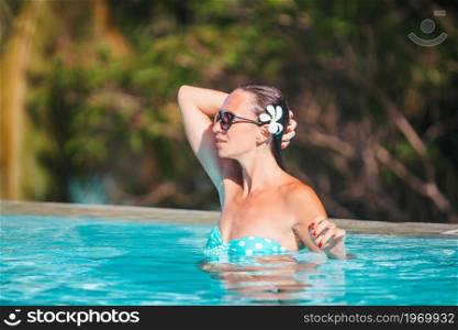 Beautiful young woman relaxing in swimming pool. Girl in bikini in outdoor pool at luxury hotel. Beautiful young woman relaxing in swimming pool.