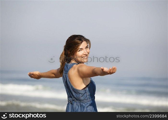 Beautiful young woman relaxing with arms open on the beach