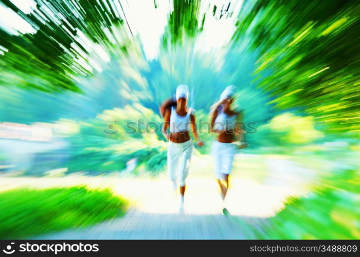 Beautiful young woman running in green park on sunny summer day