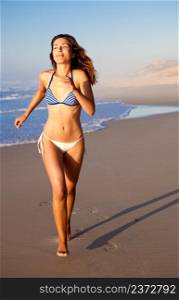 Beautiful young woman running on the beach