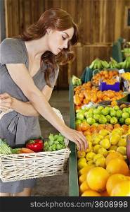Beautiful young woman selecting fruit in market