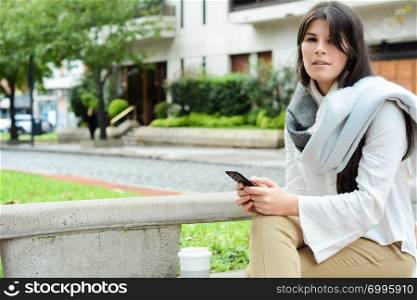 beautiful young woman sending message with smartphone on the street.