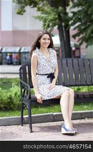 Beautiful young woman sits on a bench