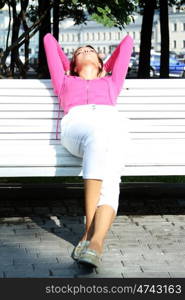 Beautiful young woman sits on a bench