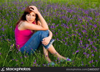 Beautiful young woman sitting on a flowery meadow