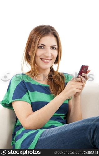 Beautiful young woman sitting on a sofa and sending a text message
