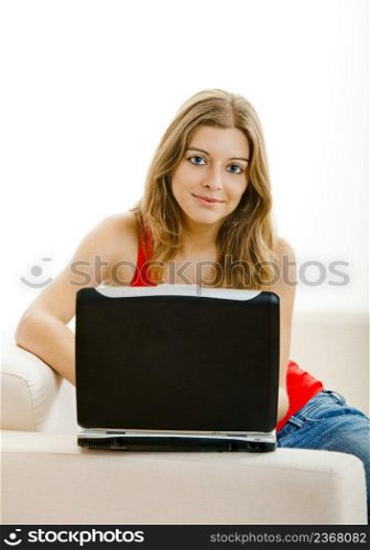Beautiful young woman sitting on a sofa and working on a laptop